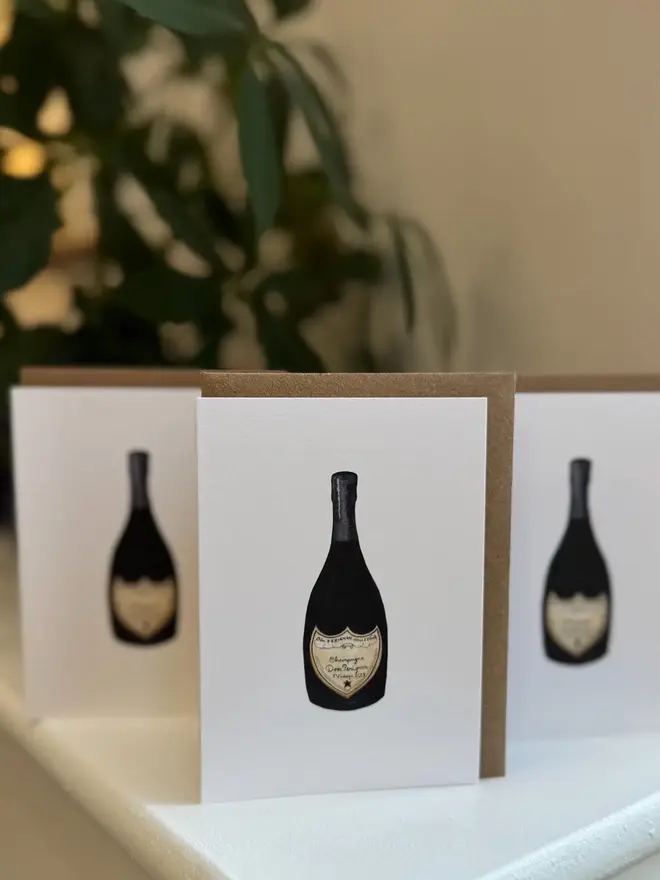 champagne bottle illustrated mini cards (pack of 3). set of 3 cards placed on mantelpiece.
