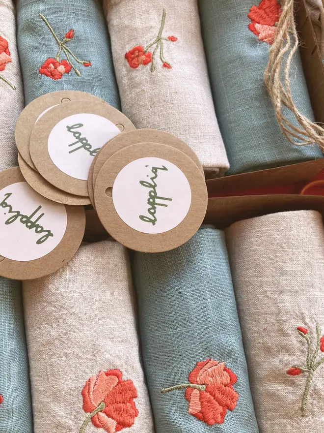 Blue and natural linen napkins embroidered with red geranium flowers.