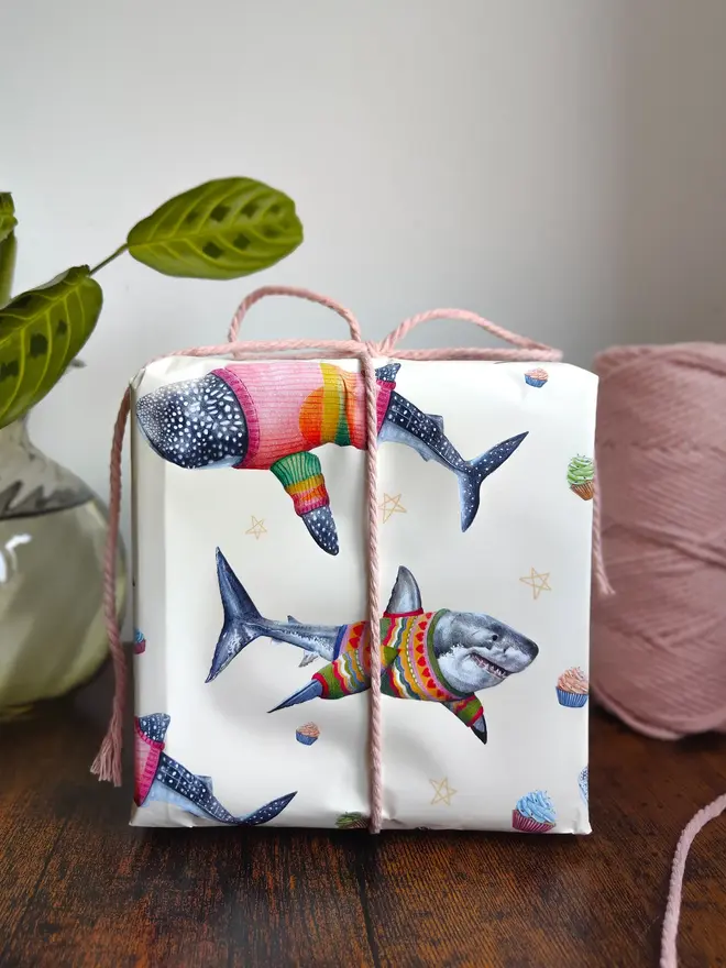 illustrated sharks in jumpers wrapping paper sheet. a sheet of cream wrapping paper featuring illustrated sharks in wooly jumpers.