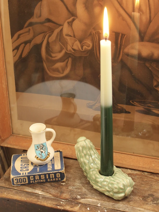 Pickle Candle Holder, a pickle candle holder sitting on a wooden surface with a candle in it. 