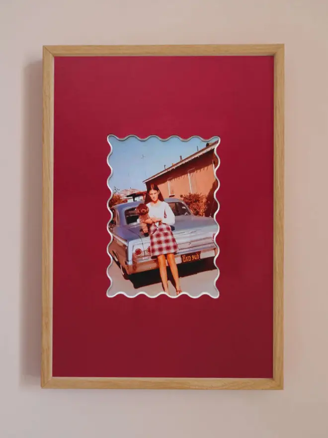 Ric rac photo mount frame with a red mount featuring a decorative ric rac boarder around a centered Instax photo, displayed on a neutral beige wall.