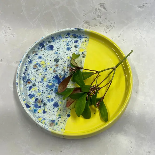 Shoreline Tray, a colourful tray placed on a stone surface accompanied by flowers. 