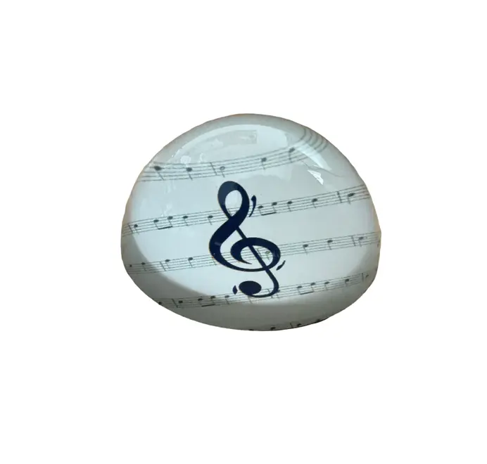 Round paperweight with a treble clef and sheet music on white background. 