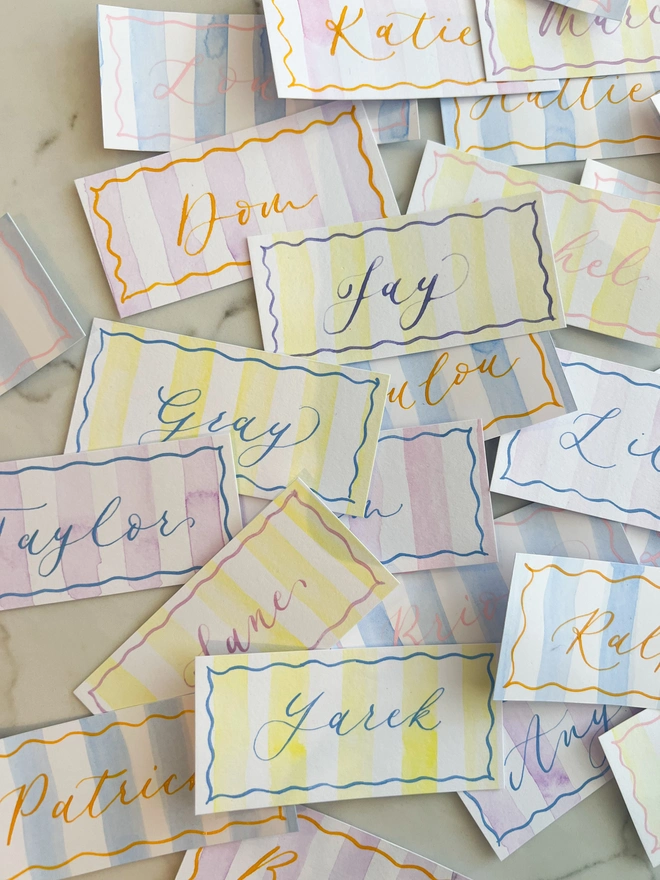 Personalised calligraphy event place cards, striped coloured place cards spread together