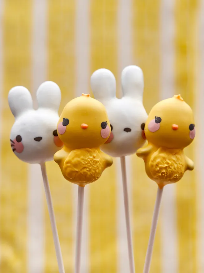 Easter Chicks and Bunny Cake Pops held up against and yellow and white backdrop 