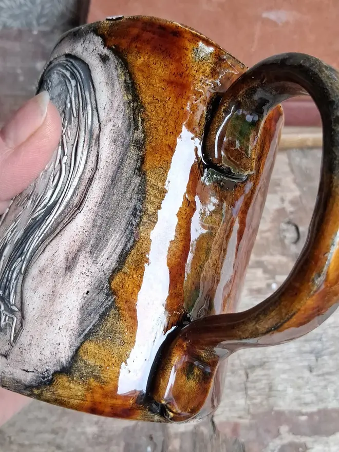 linocut owl ceramic mug.  a brown mug bearing an owl design photographed from the side.