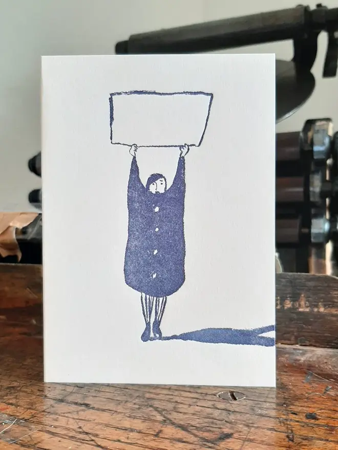 Blank Message Letterpress Handprinted Blue Greetings Card, a white card with a blue design sitting on a wooden background. 