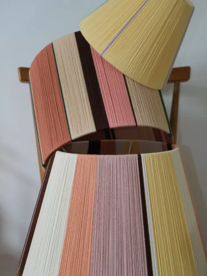 Lifestyle image of stack of lampshades with Pink and Putty lampshade in the middle