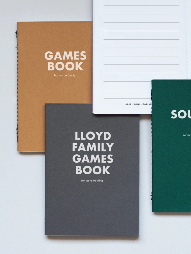 Three pocket notebooks with personalised text, one saying lloyd family games book