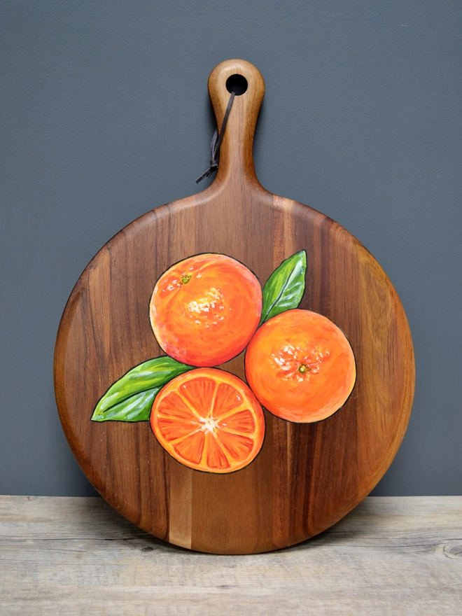 Wooden serving board with a handpainted design of some clementines
