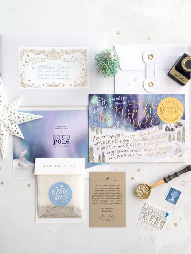 A letter from Father Christmas kit in a winter white and blue theme, laid flat. It has a white envelope with a personalised gold foil "Special Delivery" label, a white string-and-washer envelope, the illustrated "The North Pole" notecard with northern lights, snowy trees, a polar bear and a gold "Lapland Approved" seal, the "North Pole Post Office" card back, a "Sprinkle me" Magic Dust bag and a kraft instruction card from Buddy the chief elf.