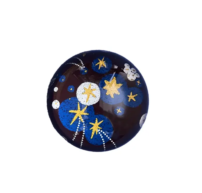 Glossy dome-shaped paperweight with gold stars on a white background. 