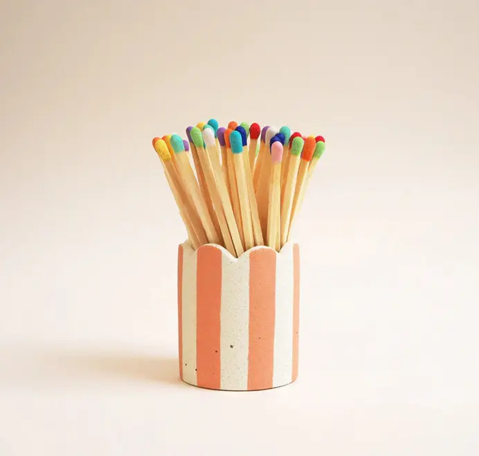 Stripy Match Stick Holders. Coloured matchsticks in a striped, scalloped matchstick holder on a white background.  