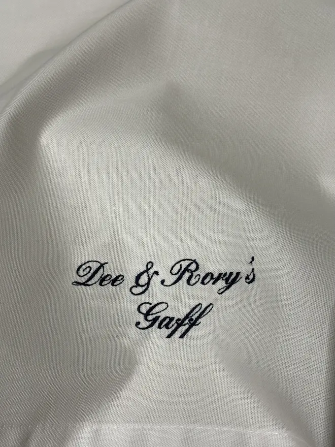 white tea towel with embroidered text in black