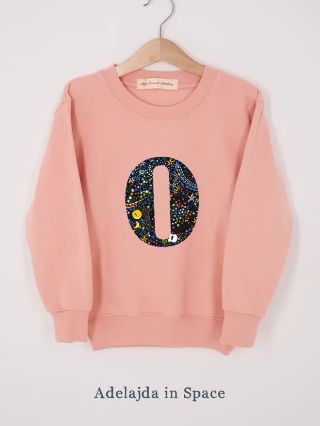 a personalised dusty pink sweatshirt with her initial sewn on the front in space liberty print 