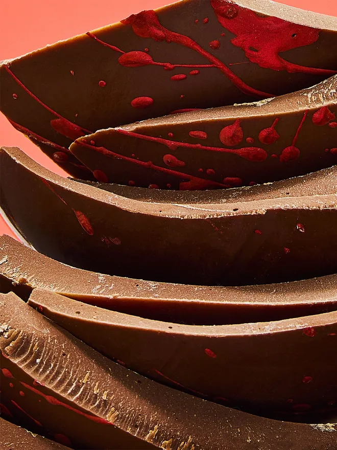 A stack of milk chocolate Easter egg pieces decorated with red speckles