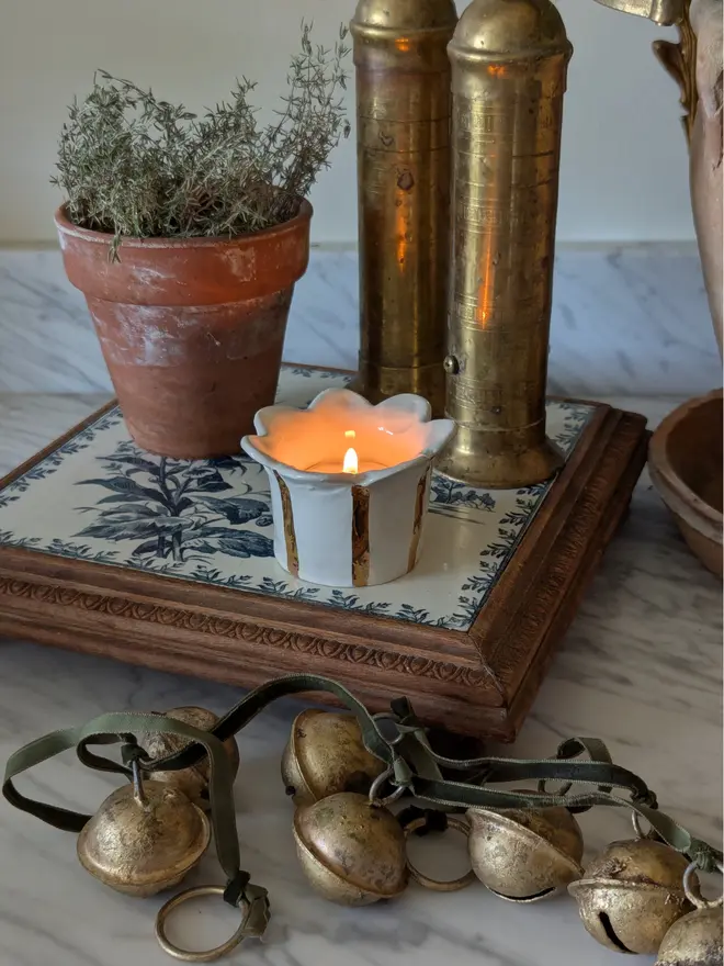 Ceramic gold Daisy tealight holder. Warm light in a Christmas setting