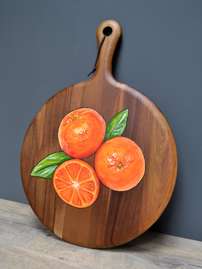 Wooden serving board with a handpainted design of some clementines