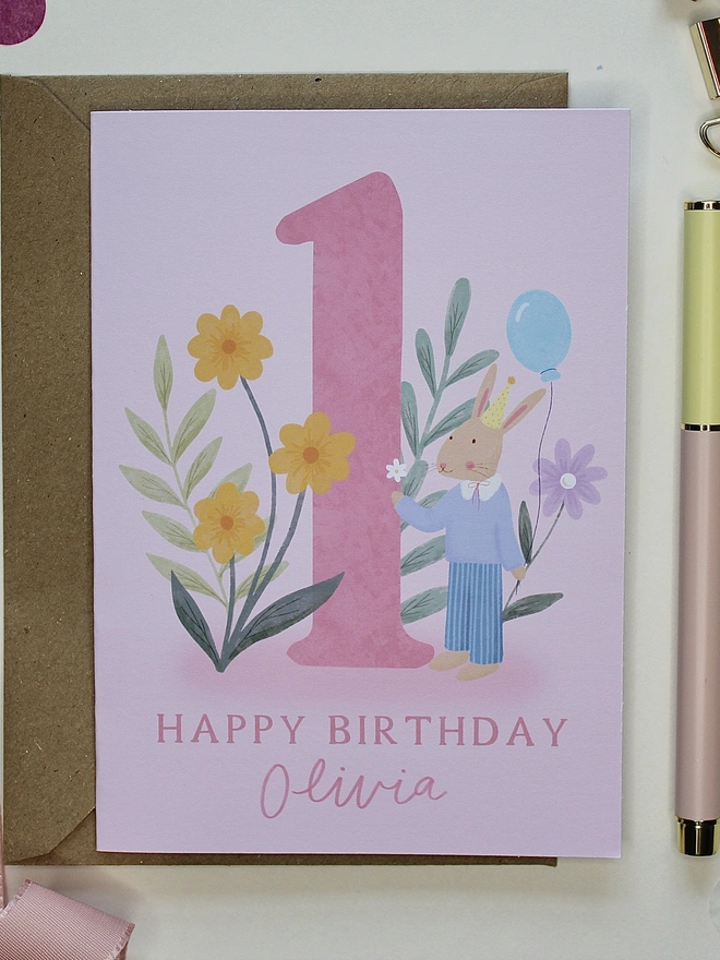 personalised floral 1st birthday card. pink 1st birthday card with illustrated rabbit and flowers.