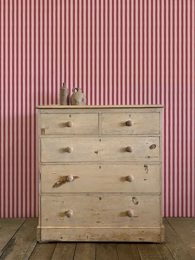 circus stripe painted wallpaper. burgundy and pink striped wallpaper on a wall.
