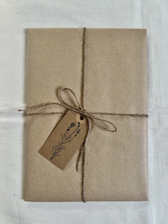 artwork gift wrapped in brown paper with a hand stamped flower tag and brown string bow