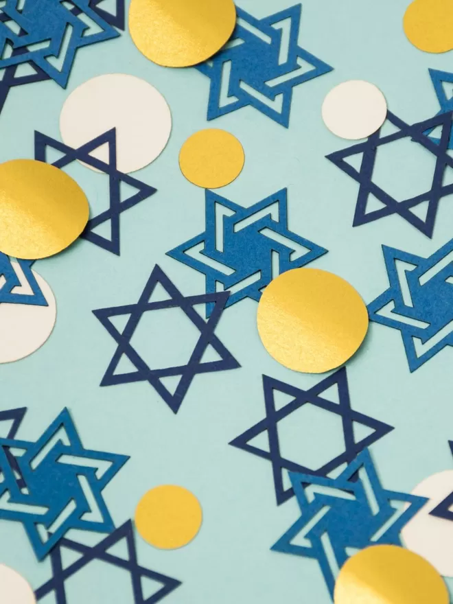 Closeup ofstar of david confetti pieces with gold and white dots.