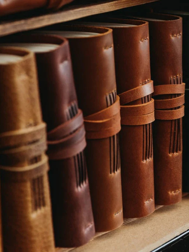leather bullet journal. a line of brown leather journals arranged on a shelf.