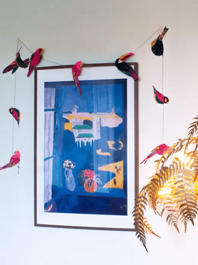 Tropical garland hanging over picture frame on a white wall