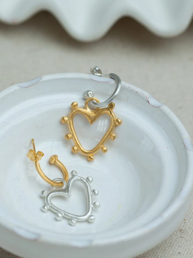 The Belong Together Hoop Earrings feature beautifully textured studded hearts in mixed metals, creating a striking contrast on classic hoops. Designed to move with you and catch the light, these statement heart earrings are effortlessly wearable — a modern symbol of connection, balance and everyday confidence.