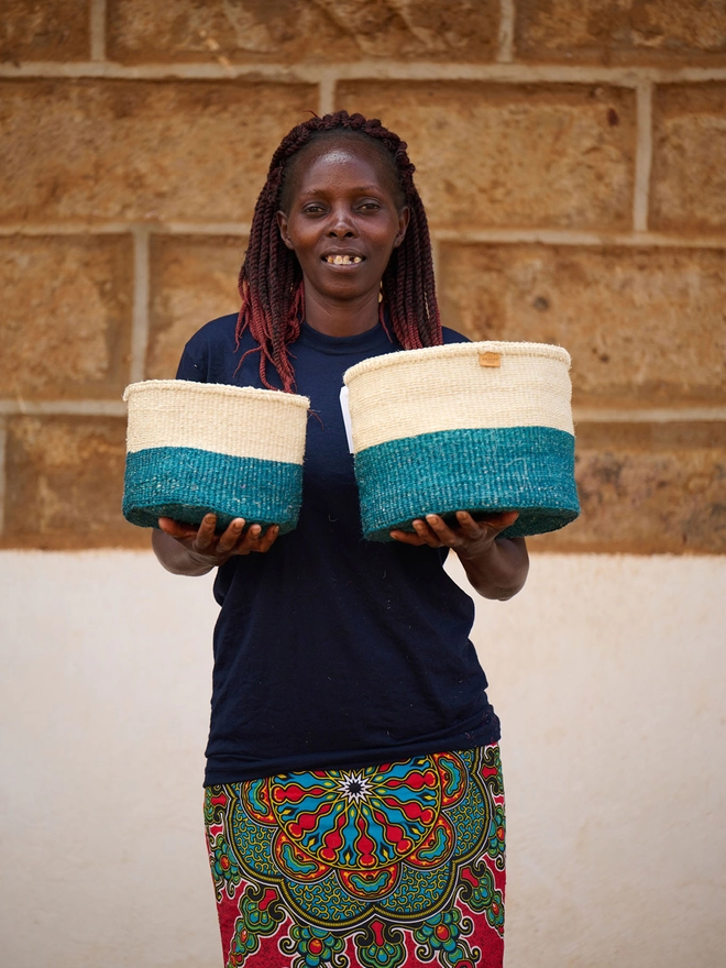weaver holding teal colour block baskets
