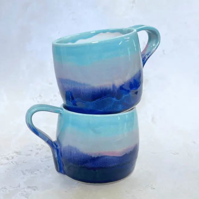 Landscape Large Round Mug, a pair of colourful coffee mugs placed on a stone surface. 