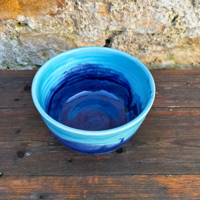 Landscape Small Bowl, a stack of colourful bowl sitting on a wooden surface against a brick backdrop. 