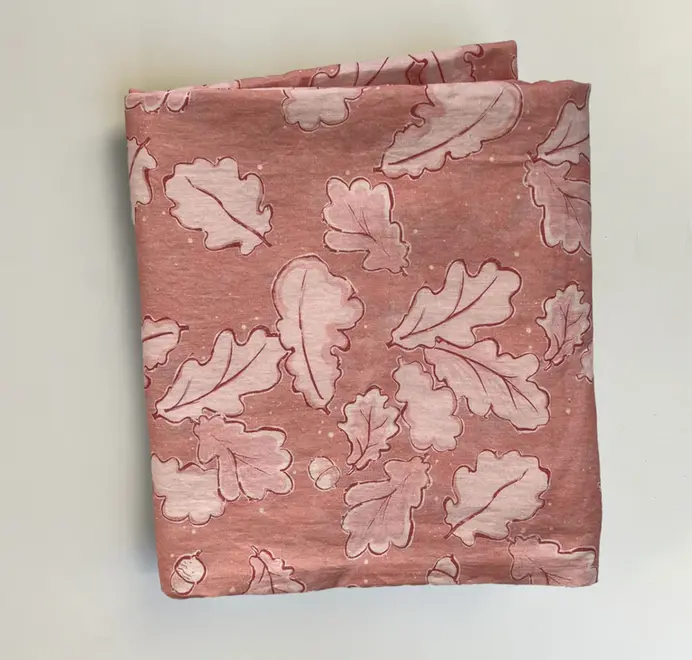 Grace Oak Trees Pink Linen Tablecloth. Light Pink and white tablecloth with oak patterns folded on a white background. 