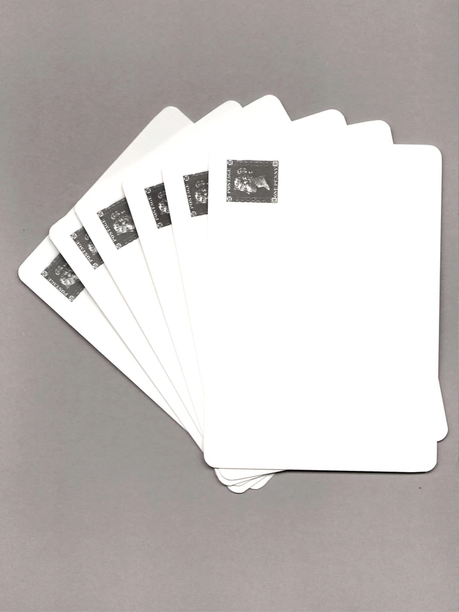 Six notecards with a black penny black stamp at the top-right corner laid out on a grey background