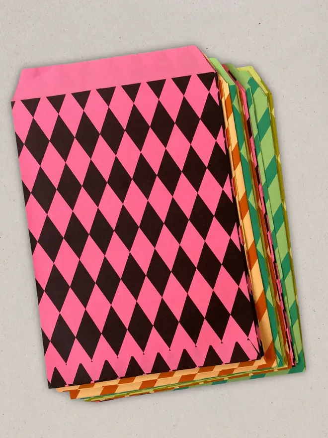 paper party favour bags (pack of 24). paper party bags in pink, orange, green and yellow stacked on top of each other.