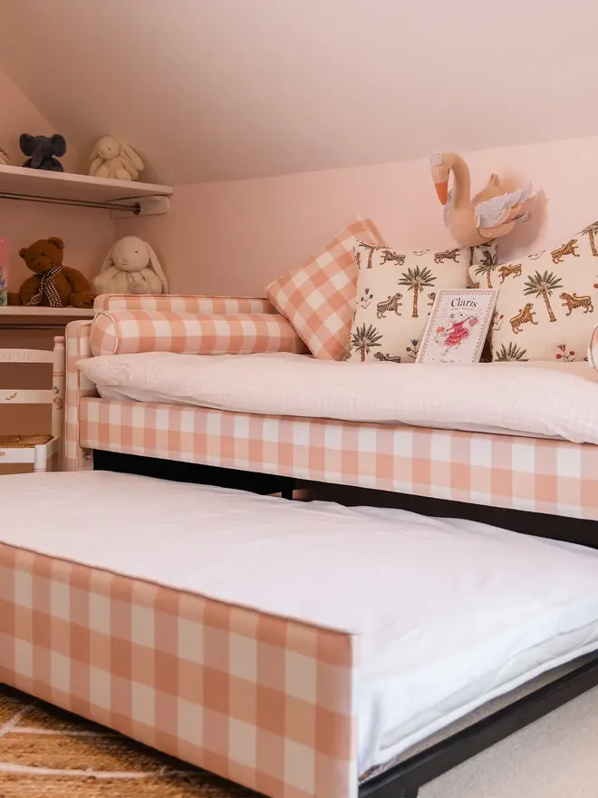 'the posie' pink gingham upholstered children's bed. a pink gingham sofa-style bed, with cushions and bedding and a pull out trundle bed.
