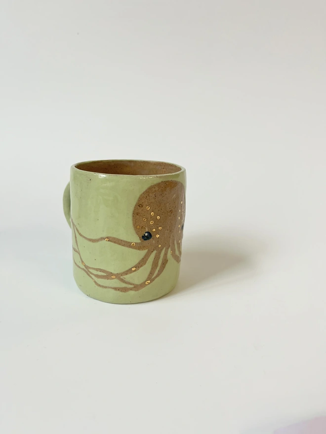 light green octopus mug, with gold detail, image made by scratching through the coloured slip to the natural clay colour underneath and glazing