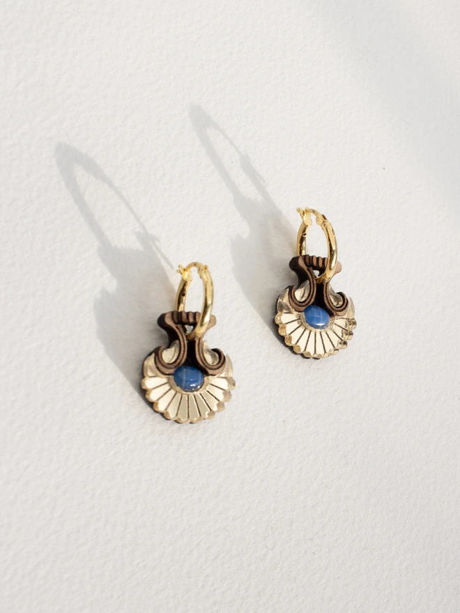Pair of gold hoop earrings with natural stones on a light gray background