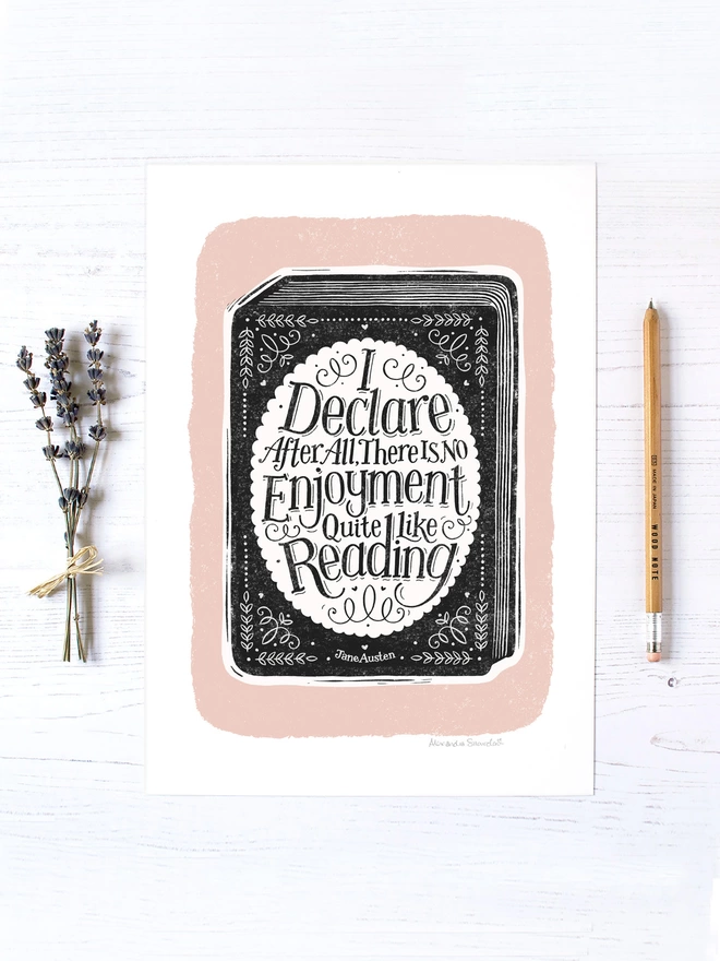 black and white book with hand lettered reading quote on a pink background with lavender and wood pencil