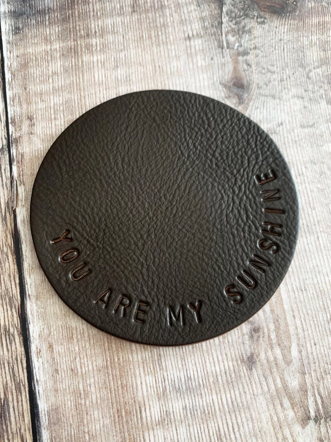 Chocolate personalised leather coaster. You are my sunshine stamped on it.