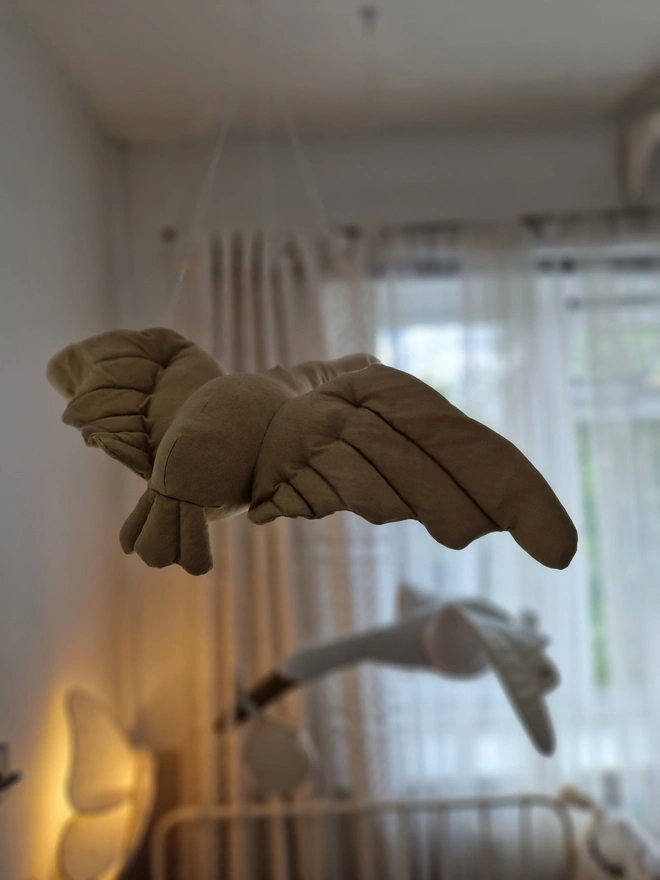 Flying Swan Hanging Decoration, a hanging beige swan decoration, suspended in a child's bedroom. 
