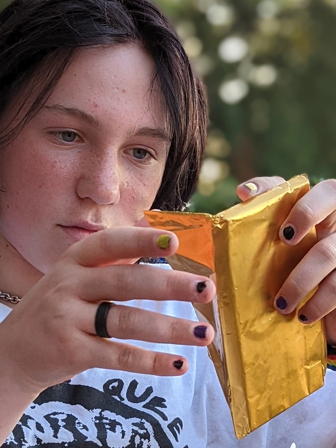 Happy young teenager opening gold foil wrapped charity caramelised chocolate bar