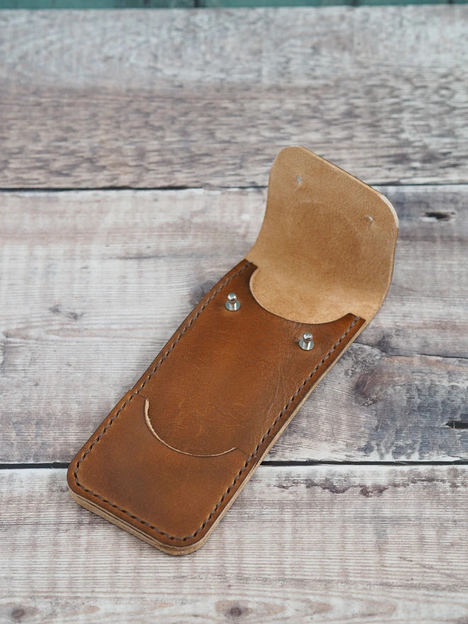 Handmade leather darts sleeve. A tan brown leather darts case sits open waiting for a set of darts to be put inside.