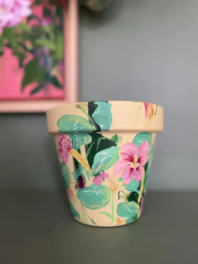 A beautifully hand painted interior terracotta plant pot. Background painted in a pastel yellow adorned in pale rose nasturtium flowers.