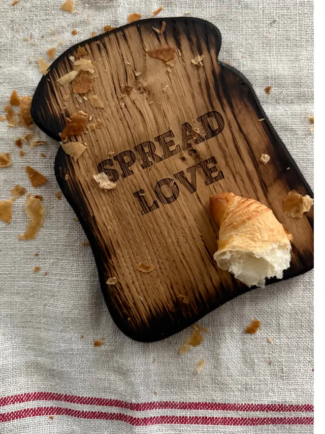 Engraved Spread Love toast board with croissant and crumbs