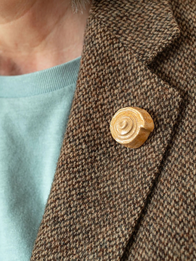 ceramic pastry pin badges. a ceramic cinnamon bun badge on a coat lapel.