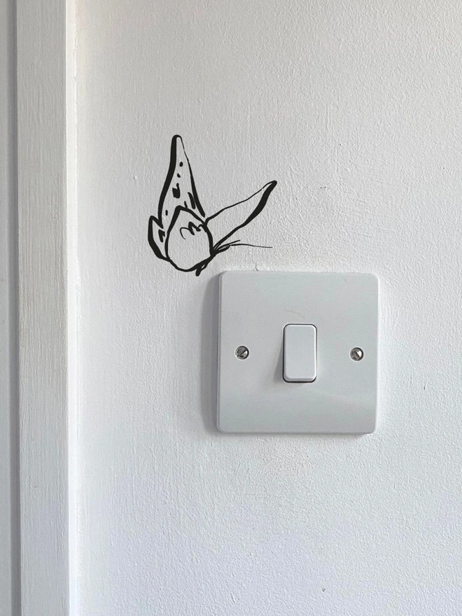 black butterfly wall sticker sitting above a light switch