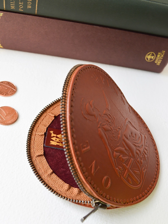 a tan leather one penny coin purse opened with a metal zip displaying natthakur logo