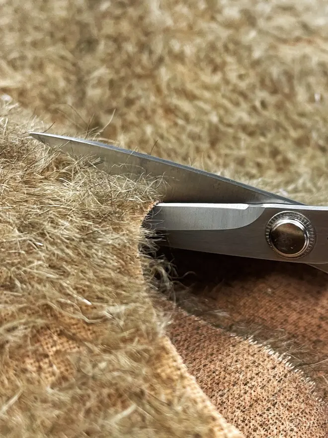 Close-up of teddy fabric being cut with scissors.
