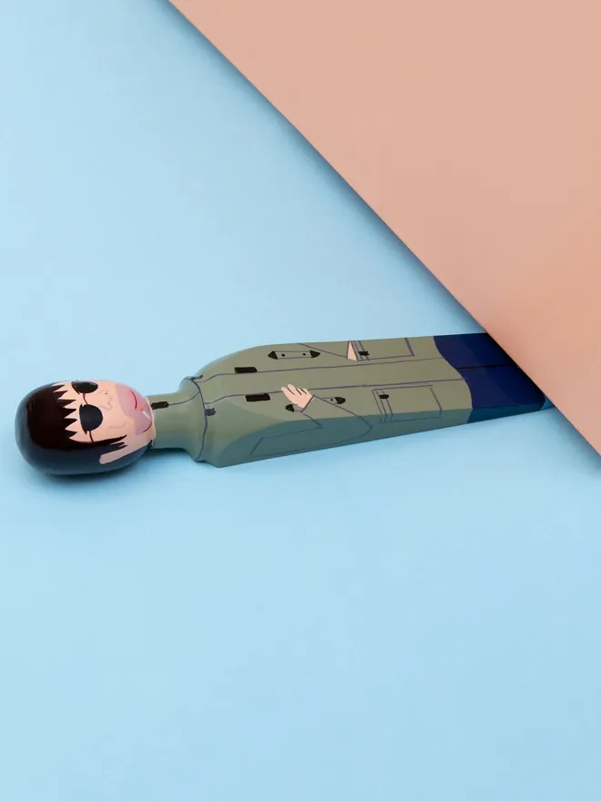 Wooden Door Stopper (Our Liam), a colourful wooden door stop sitting under a door.